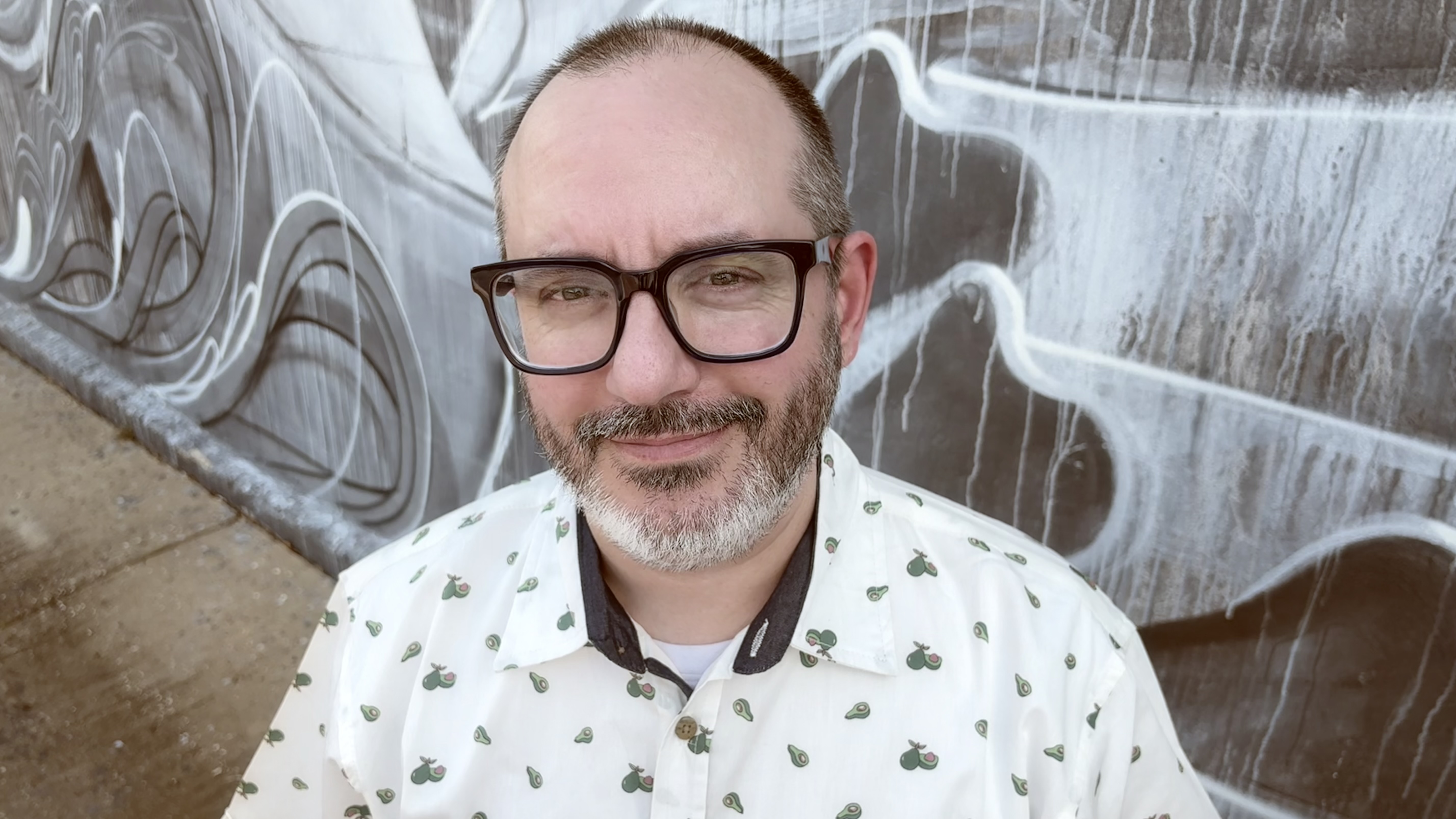 Brian Aloisio, sound designer, standing in front of a mural on 1st Ave in St. Petersburg, FL